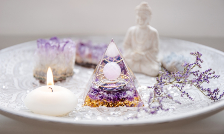 a white plate with a crystal pyramid, mini white Buddha statue, amethyst crystals, mini white candles and fresh sprigs of lavendar