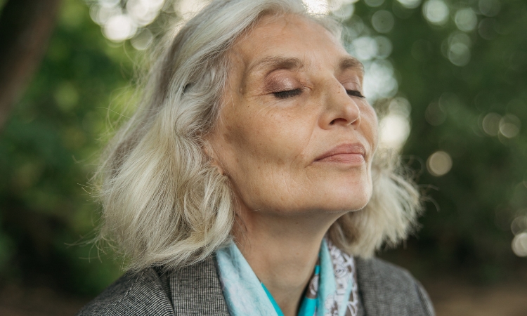 beautiful grey haired woman head slightly raised, with eyes closed in mindful state