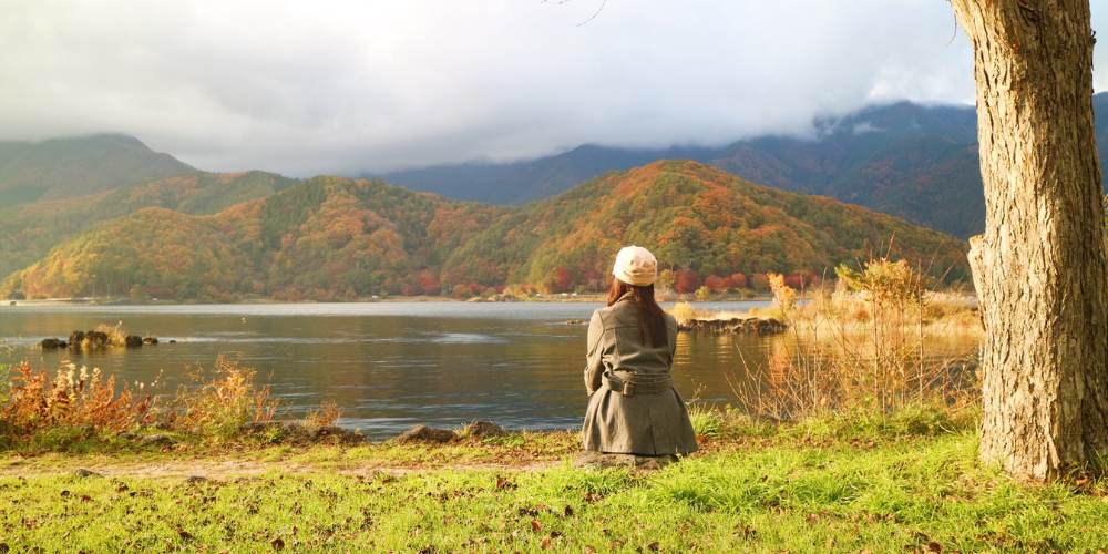 woman sitting on grass by a lake